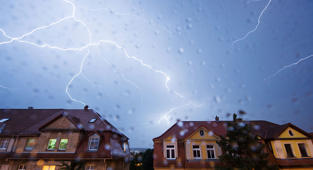 Blitze am Himmel über Wohnhäusern